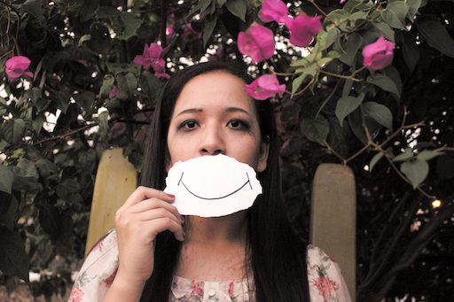 woman holding piece of paper with smile over mouth