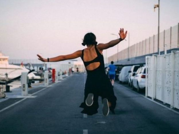 Teenage girl jumping in the air outdoors during the summer holidays, representing freedom, energy and teenage wellbeing.