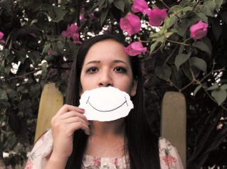woman holding piece of paper with smile over mouth