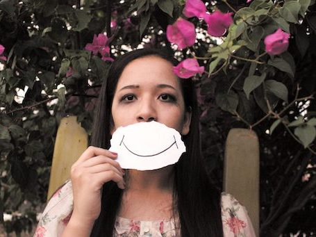 woman holding piece of paper with smile over mouth
