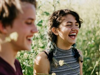 Two young adolescents laughing together outdoors, sharing a relaxed moment of friendship and connection.