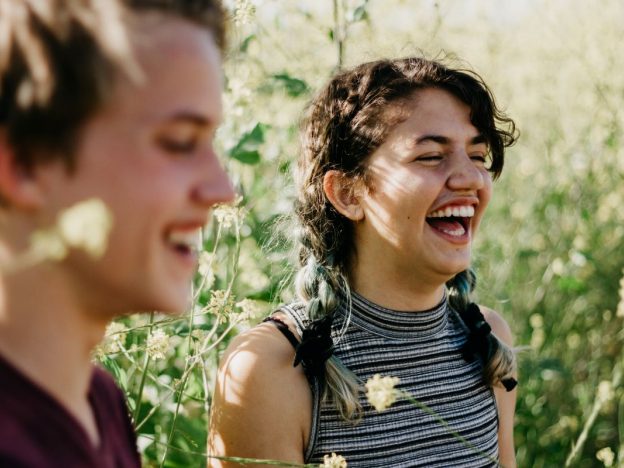 Two young adolescents laughing together outdoors, sharing a relaxed moment of friendship and connection.