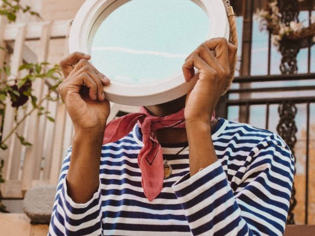 Young person holding a mirror in front of their face