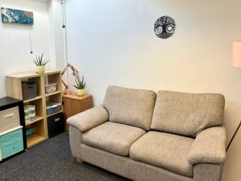 Comfortable sofa, warm lamp and plants in a welcoming Chichester counselling room