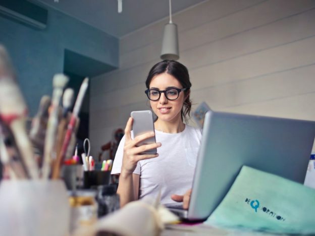 Teenager sitting at a desk, looking thoughtful or stressed, with books and a laptop in front of them.